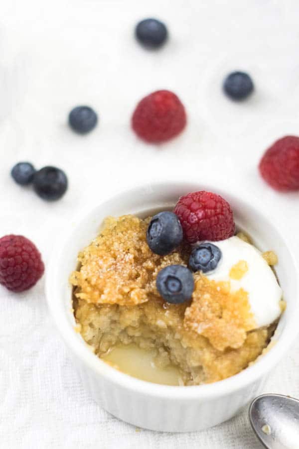 Oatmeal Brulee in a white ramekin with the sugar crust bren and topped with fresh berries.