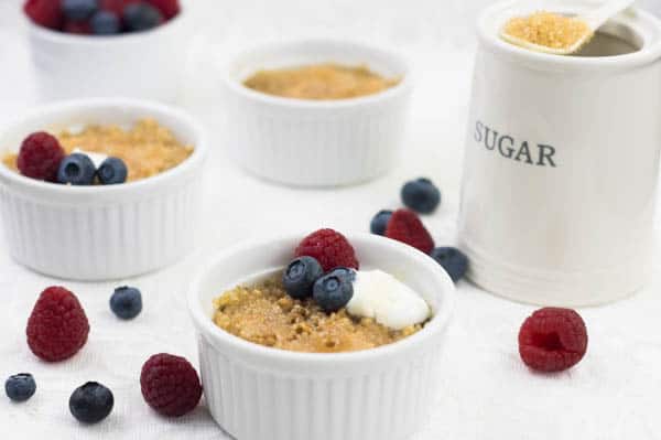 Oatmeal Brulee in ramekins on a table next to a jar of sugar.