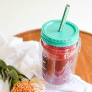 Close up of an insulated cup with a red smoothie.