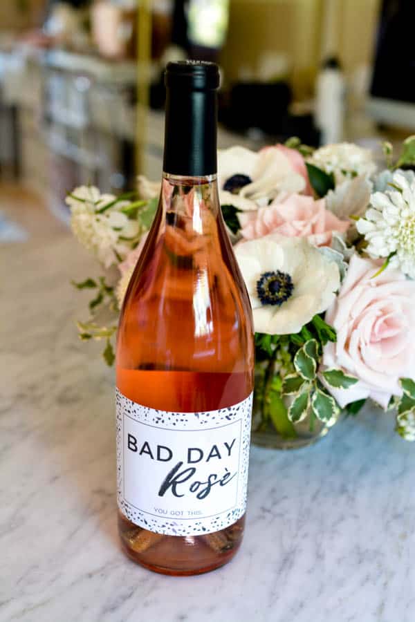 A bottle of rosé on a table in front of flowers with a label that says "Bad Day Rosé".