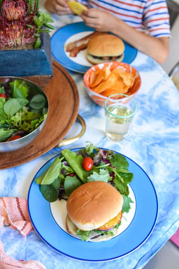 A BBQ Pineapple burgers on a plate next to a salad. 