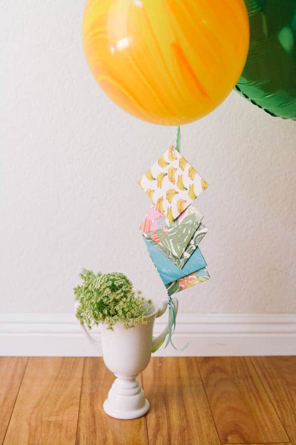 Graduation balloon bouquet with attached gift cards in paper envelopes tied to the handle of a ceramic trophy.