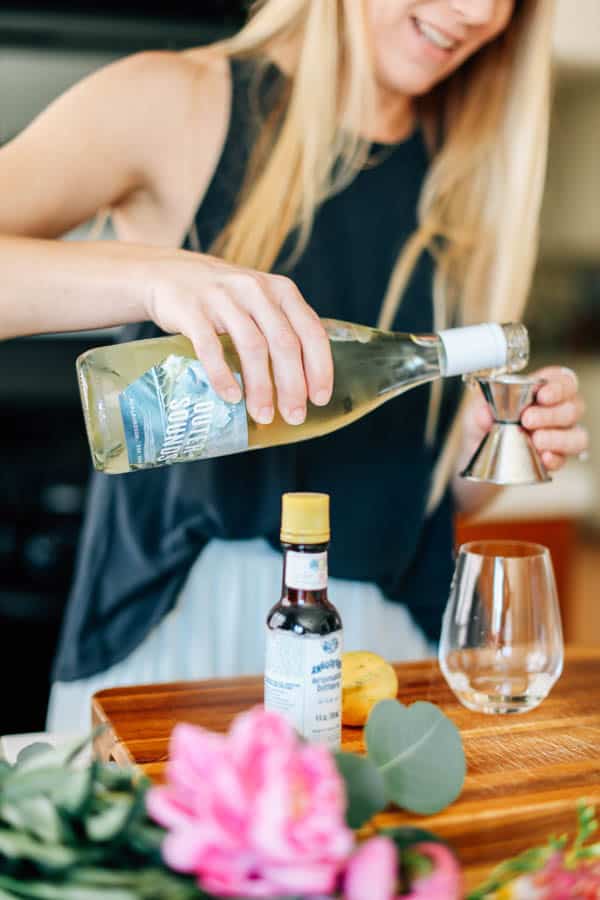 Woman pouring white wine into a cocktail jigger.