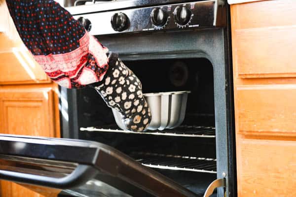 Woman adding a bundt pan to the oven.