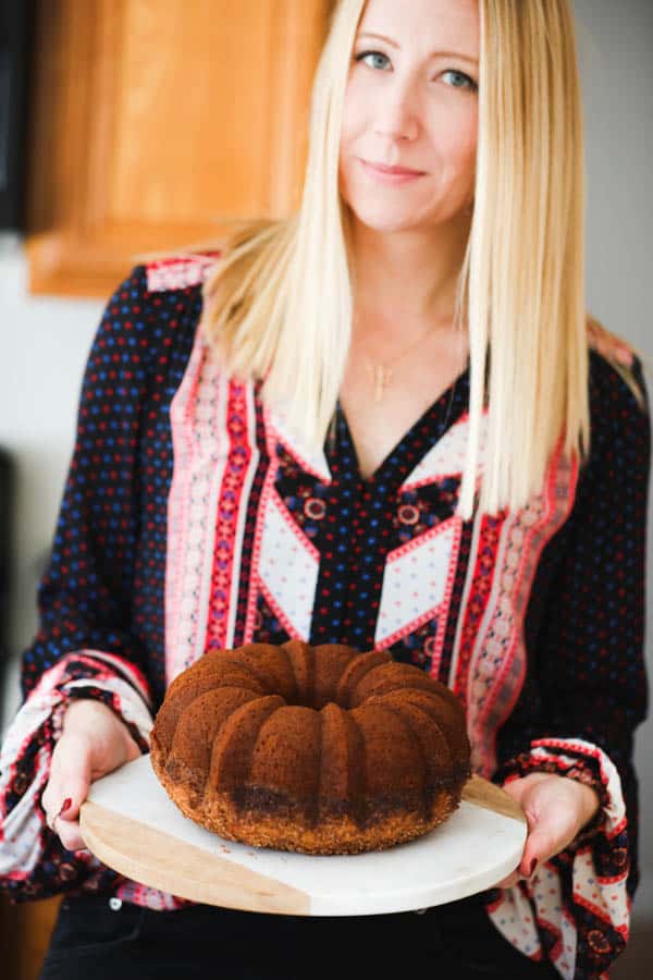 Blond woman holding a rum bundt cake.