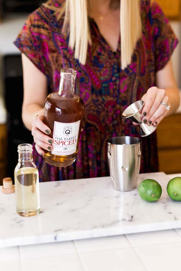 Woman pouring spiced rum into a cocktail shaker.