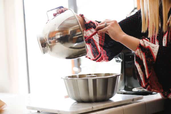 Woman adding cake batter to a bundt tin.