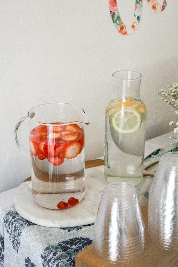 Pitchers of water on a table with sliced fruit in them.