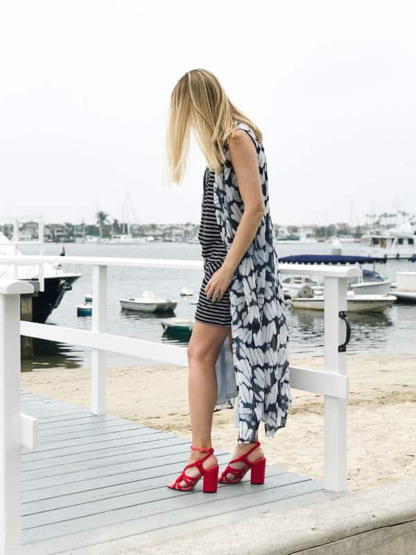 Women in red sandals and romper with a shirt dress over it.