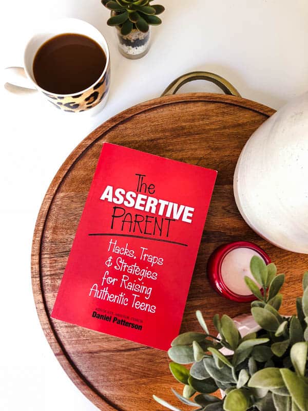 A book about assertive parenting teens on a table next to coffee. 