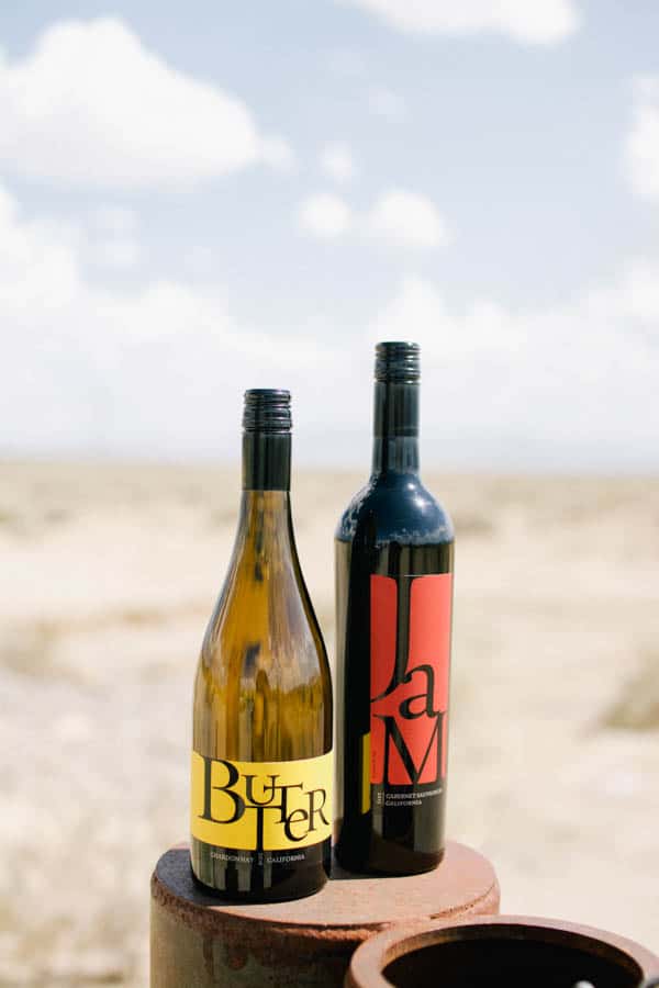 Close up of JaM Butter and Cabernet wine bottles on a fence post in the middle of nowhere.