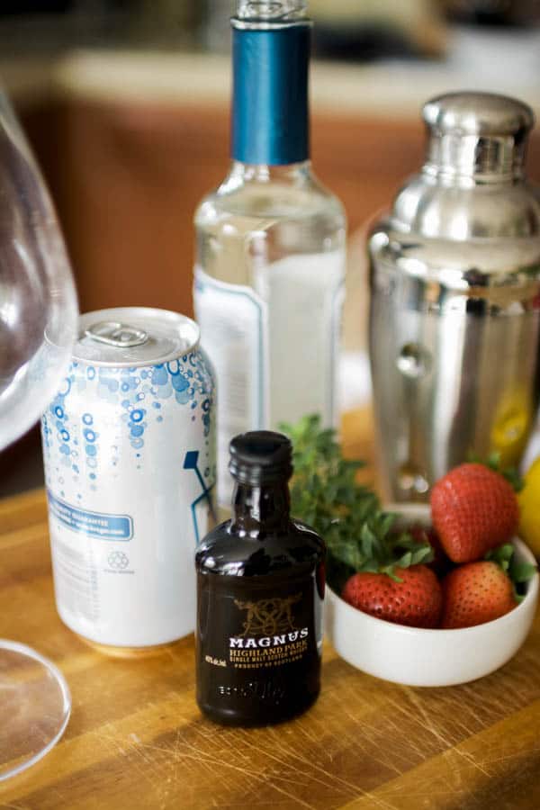 Ingredients on a cutting board to make a strawberry whiskey sour.