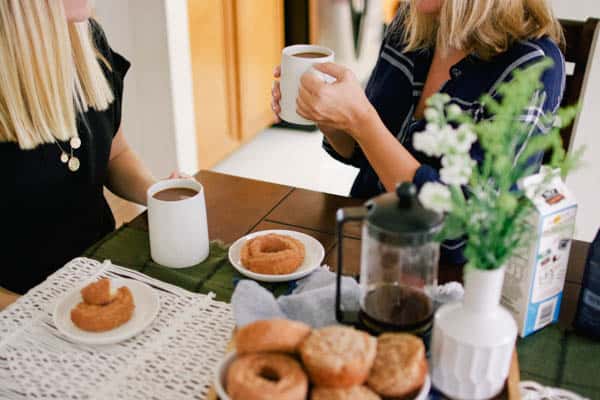 Two friends sitting at a table drinking coffee. 