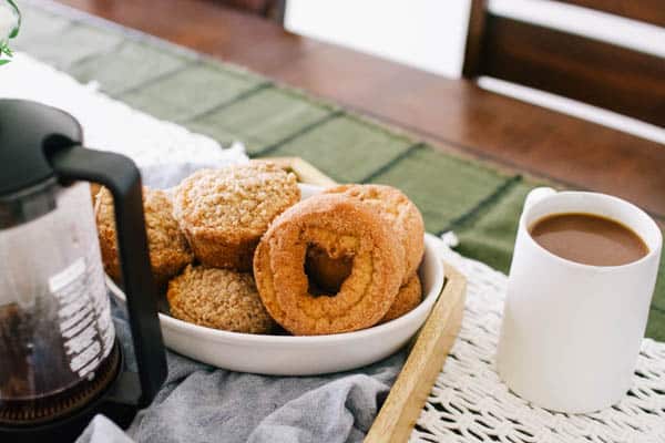 A small white bowl of donuts on a table. 