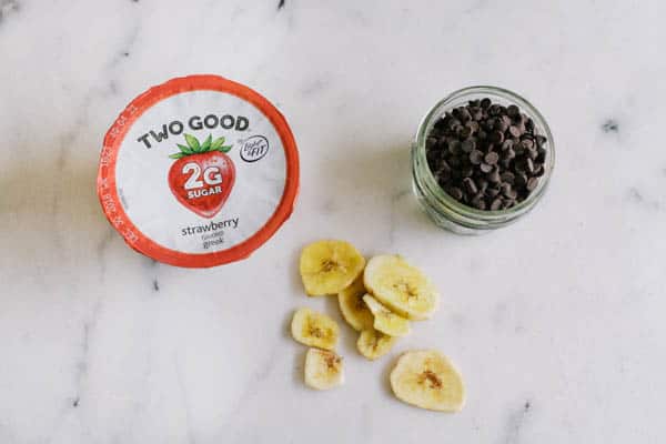 Overhead view of strawberry yogurt, banana chips and mini chocolate chips.