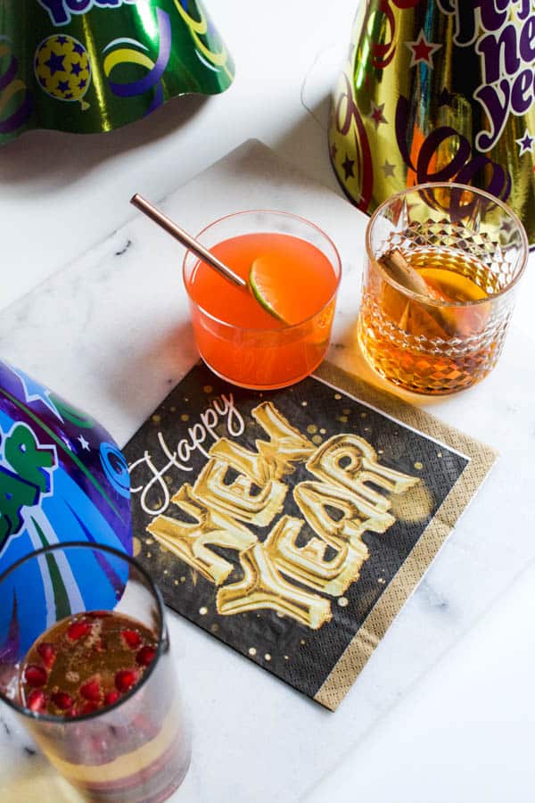 Close up image of New Year's Eve cocktails next to paper napkins and party hats.