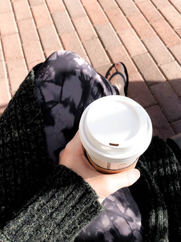 Woman sitting on a bench with a cup of coffee.
