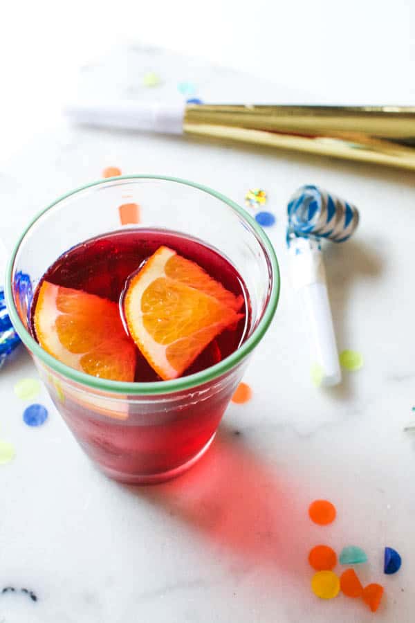 Close up image of a kid's New Year's drink with confetti and noisemakers.
