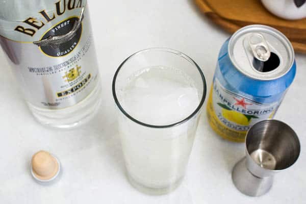 Tall cocktail glass next to a Pelleginio and a bottle of vodka.