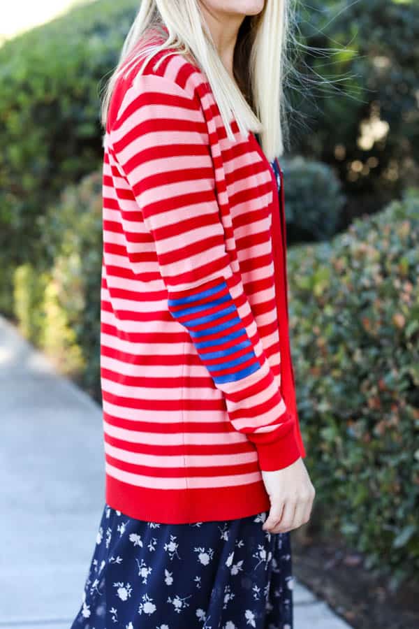 Close up of a pink and red cardigan with blue detail on the sleeve. 