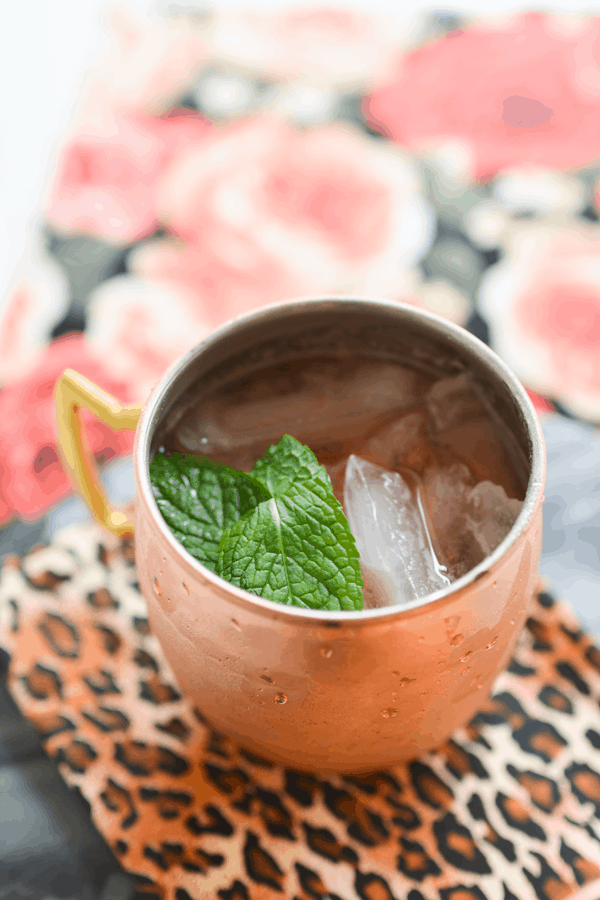 Overhead view of a strawberry moscow mule in a copper mug on a leopard print napkin.