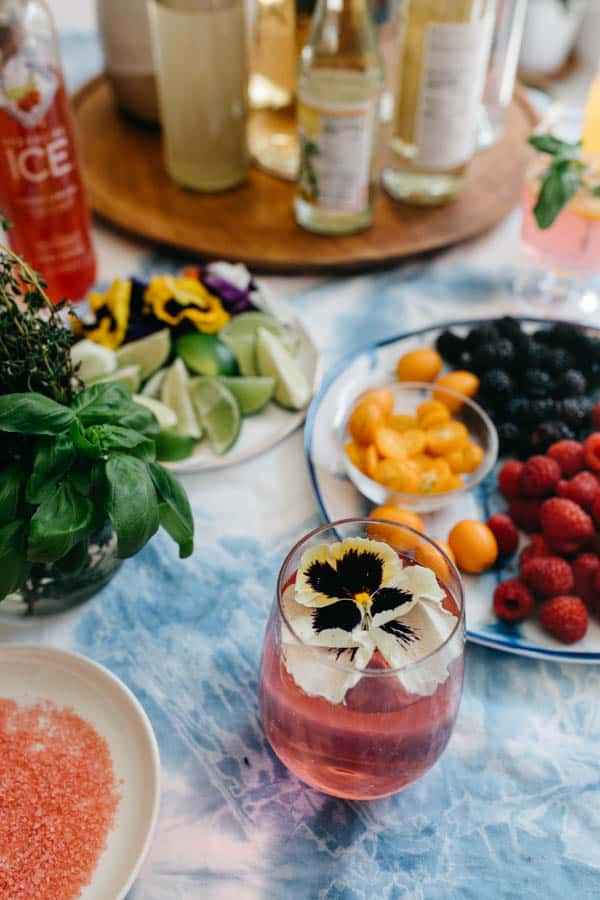 A flower garnished mocktail mimosa on a brunch beverage table. 