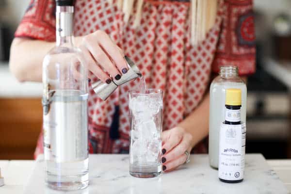 Woman pouring vodka into a tall cocktail glass with ice. 