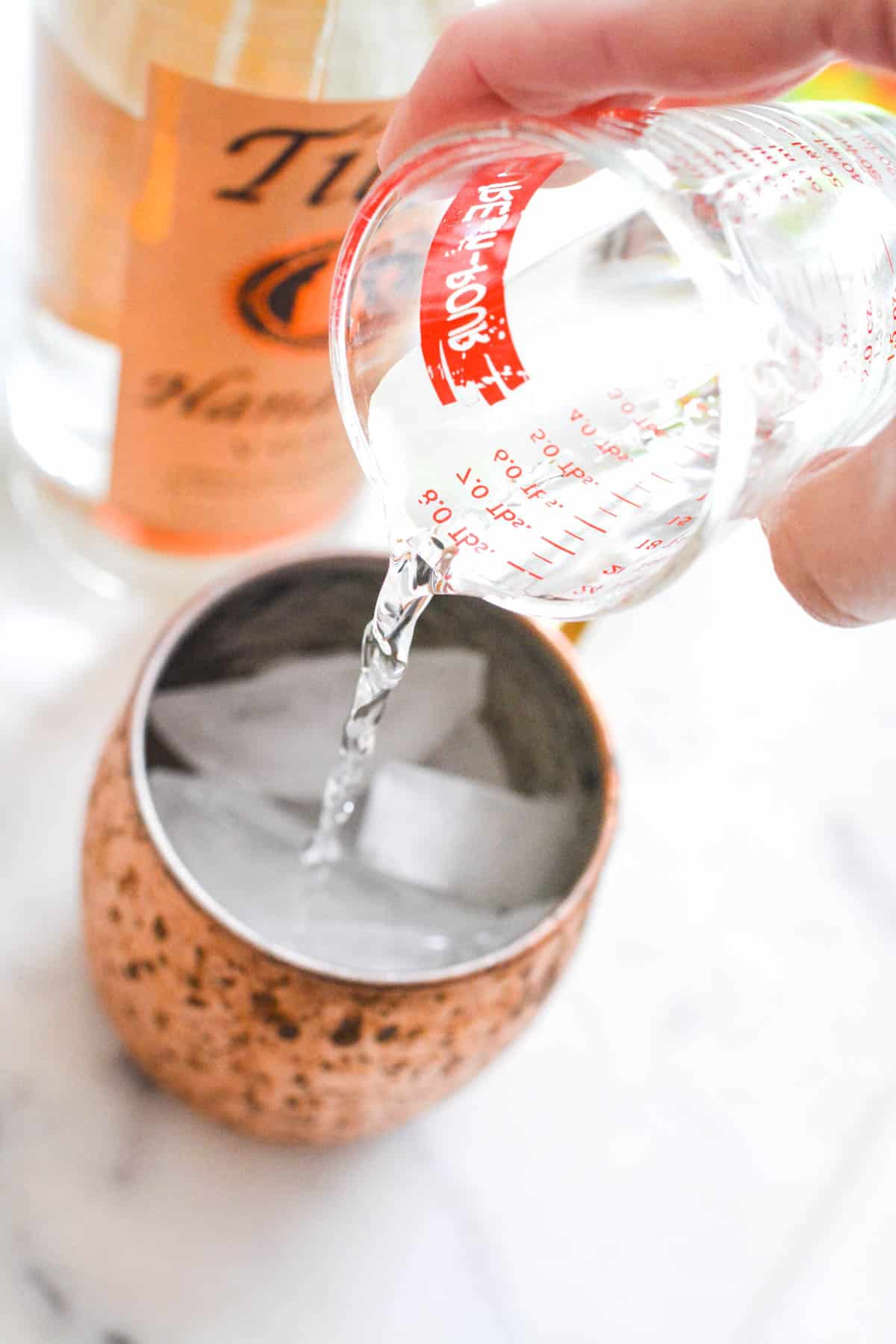 Close up of vodka being added to a Moscow mule mug.