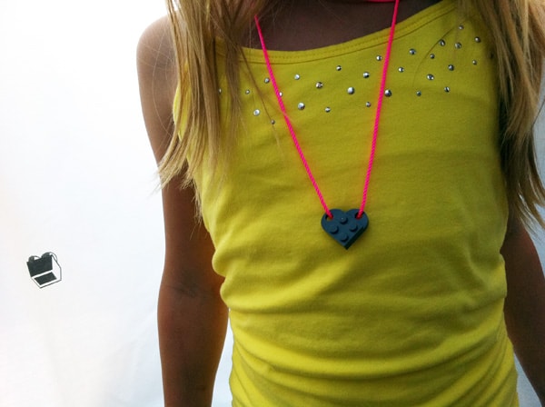 A girl wearing a necklace that is made from Legos that looks like a heart.