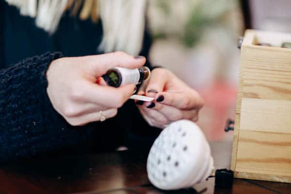 Woman adding a few drops of essential oils to a small pad for a diffuser.