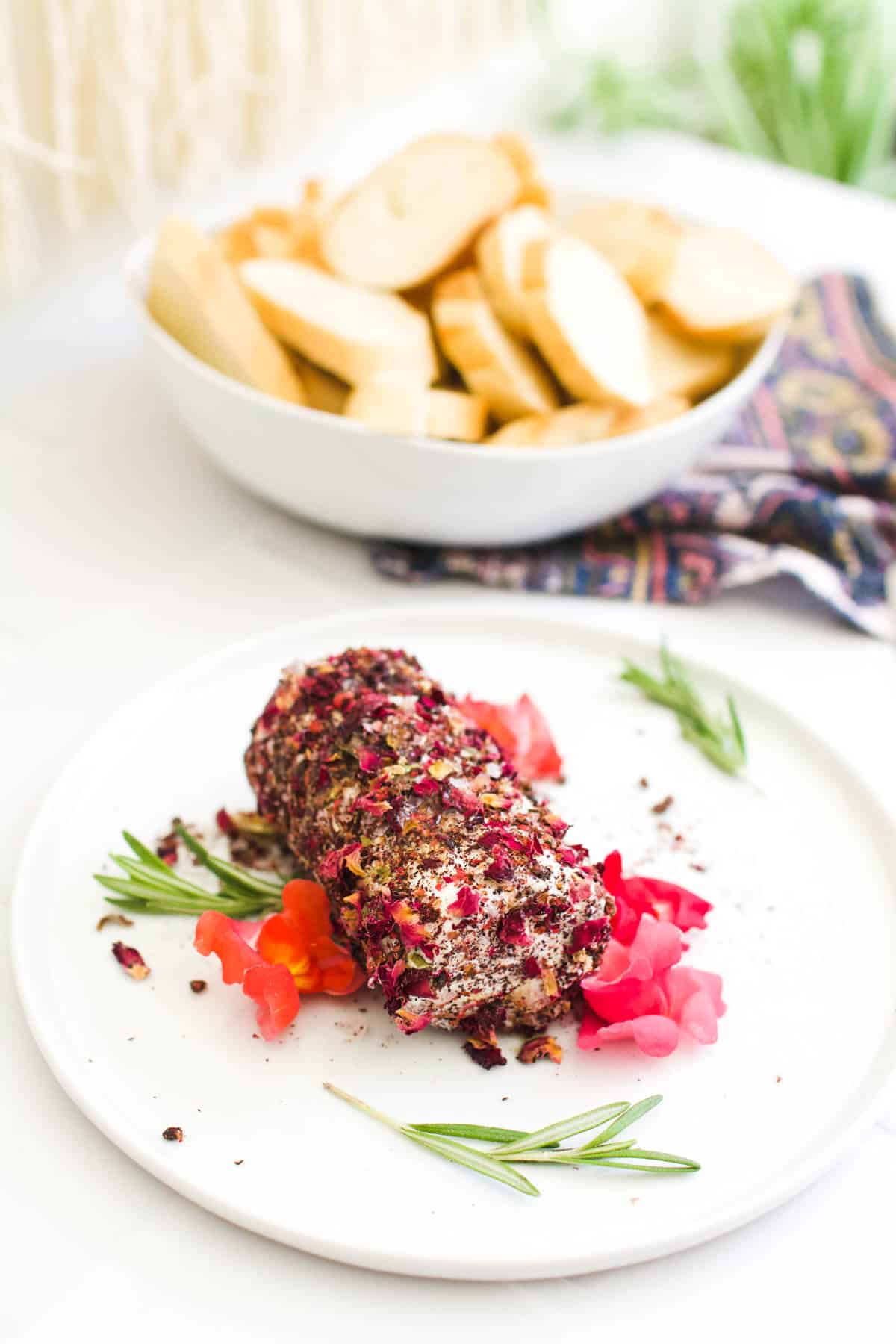 An easy appetizer with goat cheese on a plate next to a bowl of sliced bread.