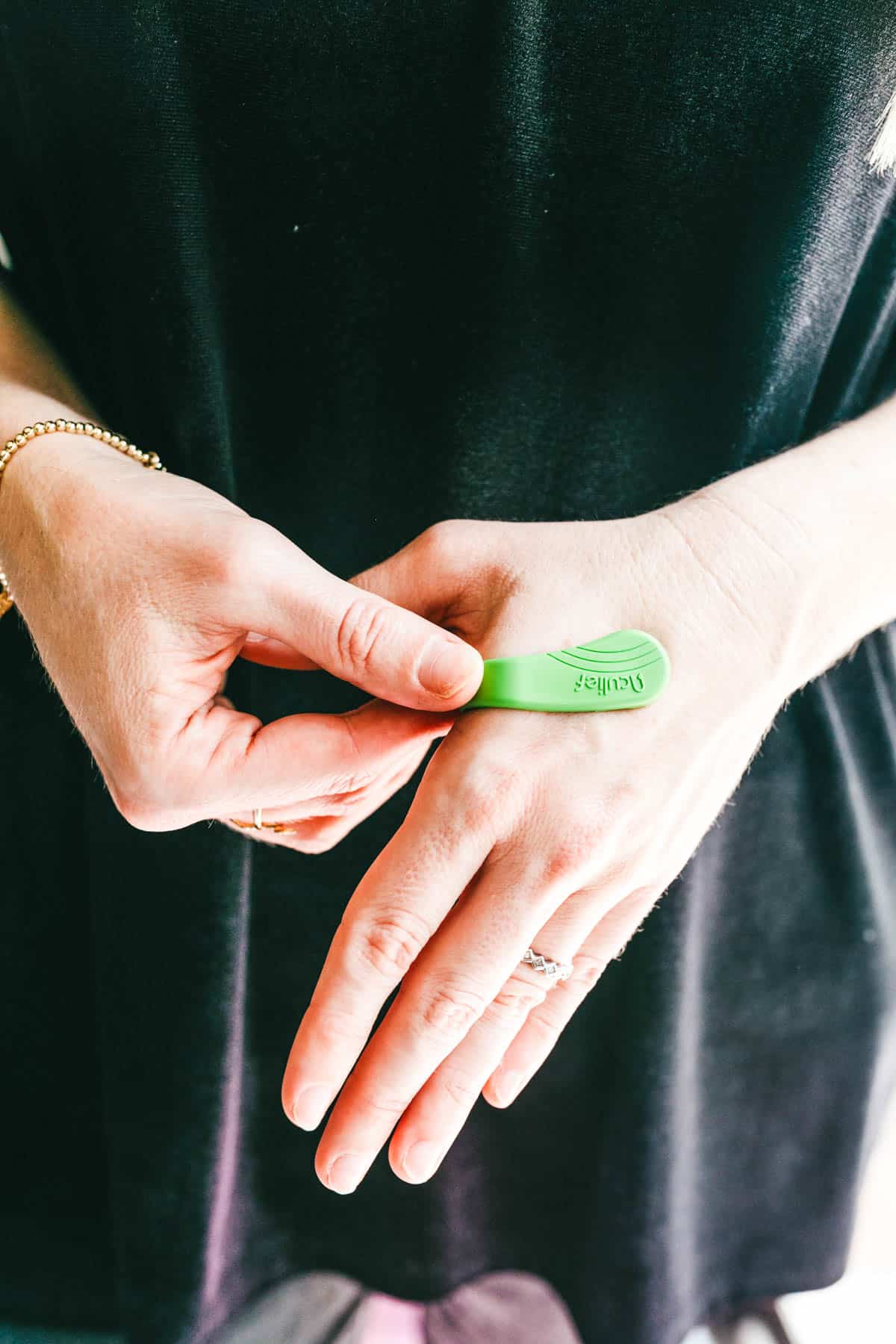 Woman putting an Aculief acupressure clip on her hand.