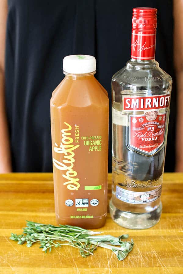 2 ingredient apple juice cocktail with apple juice and vodka sitting on a cutting board.