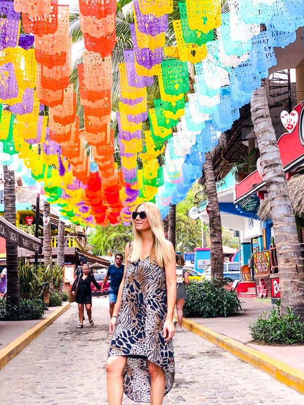 Women standing under colorful papel picado in Sayulita.