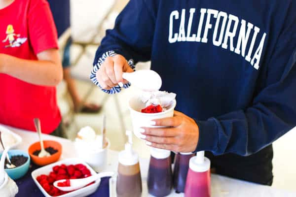 girl adding toppings to her ice cream. 