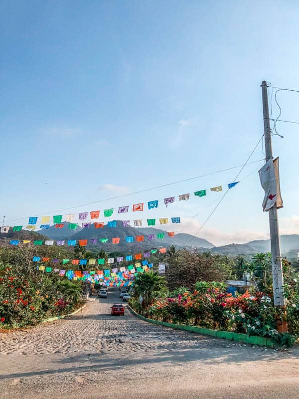 street in Mexico with colorful papel picado strung across the street from light posts.