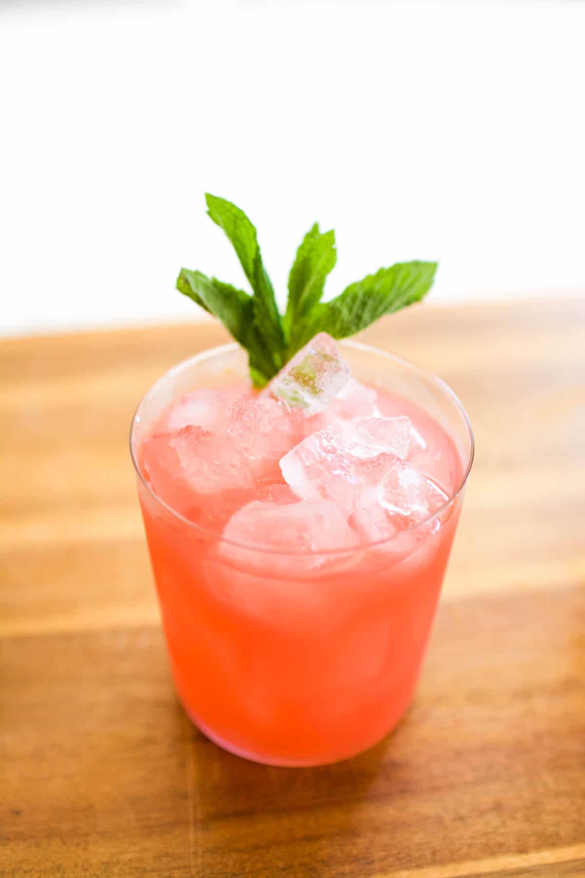 A pink drink with mint garnish on a cutting board.