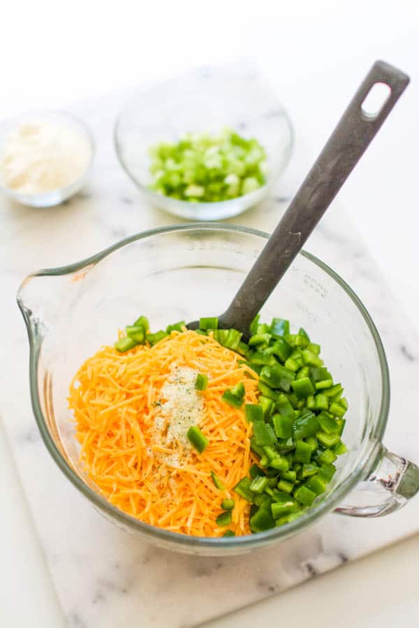 Ingredients in a mixing bowl including cheese and jalapeno.