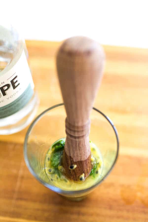 A muddler in a glass with lime, mint and passion fruit