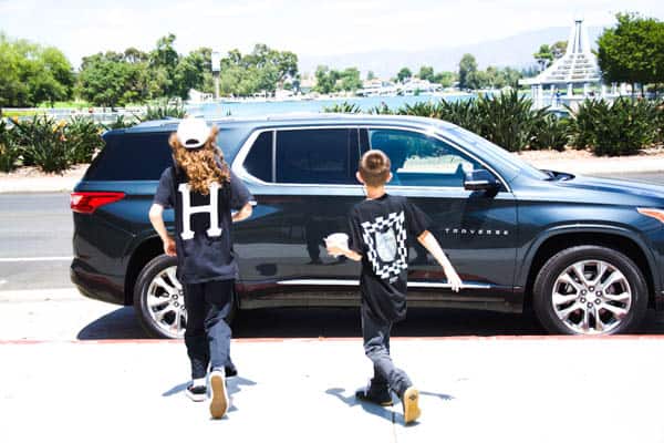 Two boys walking towards a parked Chevy Traverse