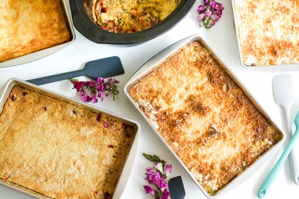 a variety of dump cakes on a table next to flowers and spatulas