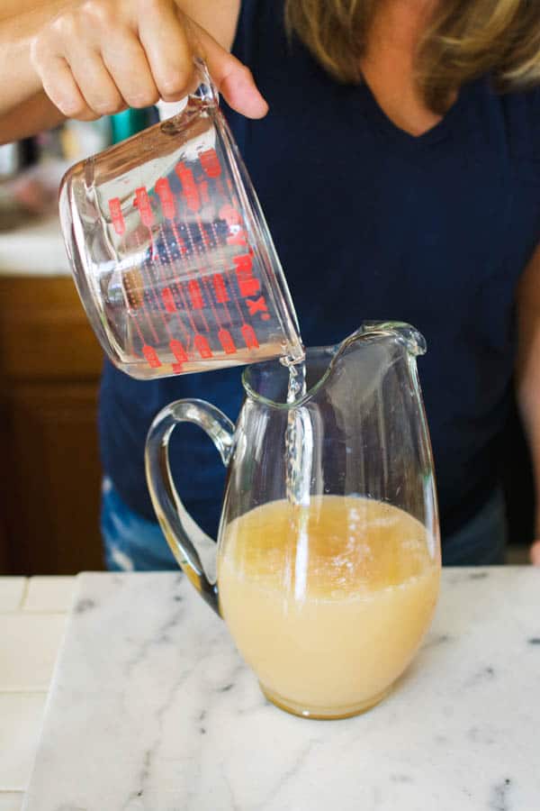 Pouring ingredients into a pitcher for a Halloween alcoholic punch recipe.