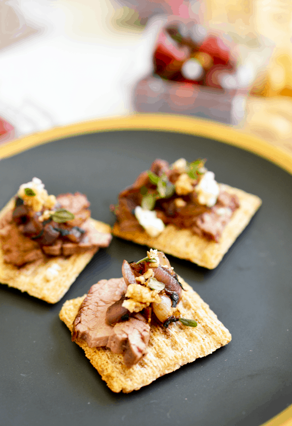 Steak bites appetizer with blue cheese and onion on a gray plate.