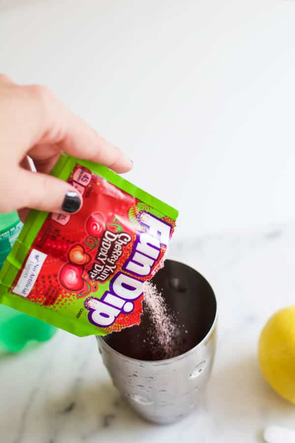 Woman pouring a package of cherry Fun Dup into a cocktail shaker. 