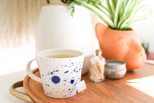 Hot green tea toddy in a mug sitting on a tray on a table.