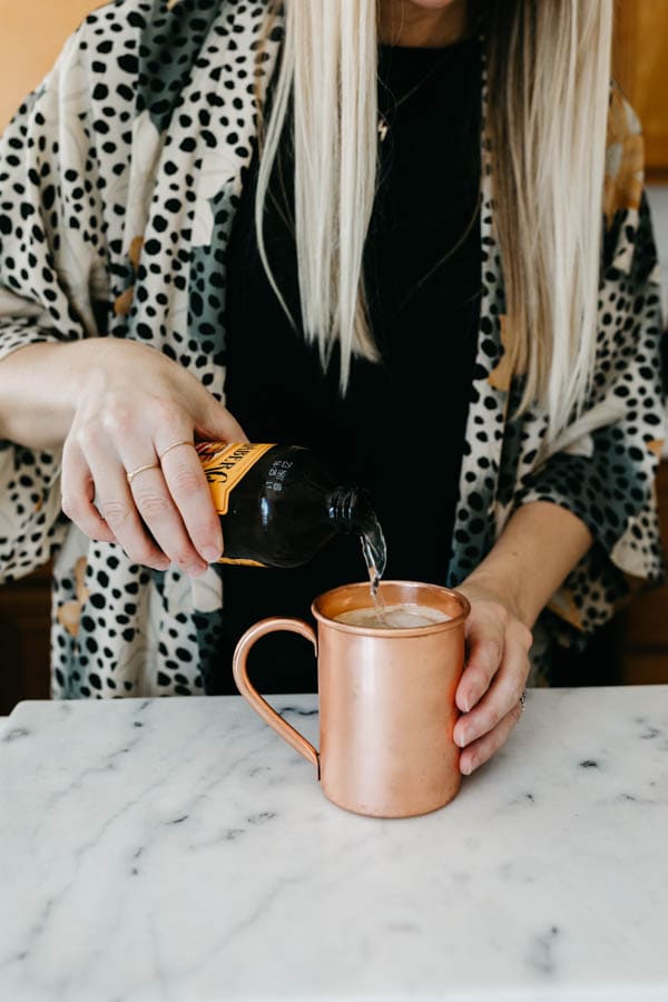 Pouring ginger beer into a copper mug.