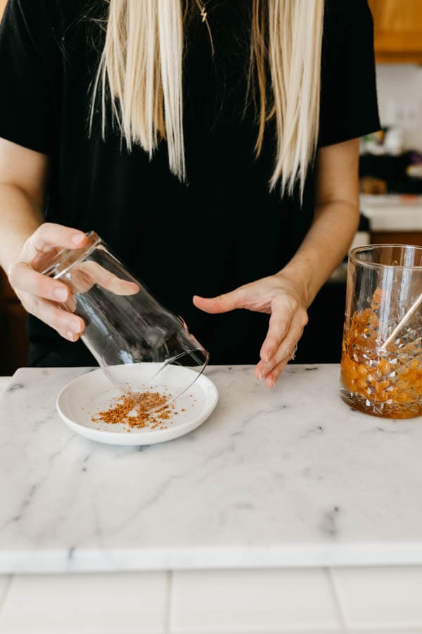 Adding Tajin to the rim of a glass for a Pumpkin Michelada.