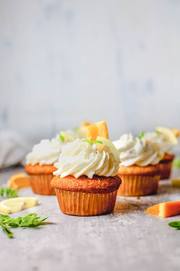 several sangria cupcakes on a table with fruit garnish