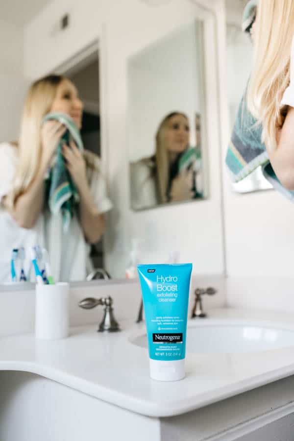 Woman drying her face with a towel after exfoliating for smoother skin.