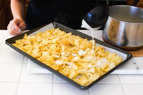 Add blue cheese sauce to potato chips on a sheet pan.